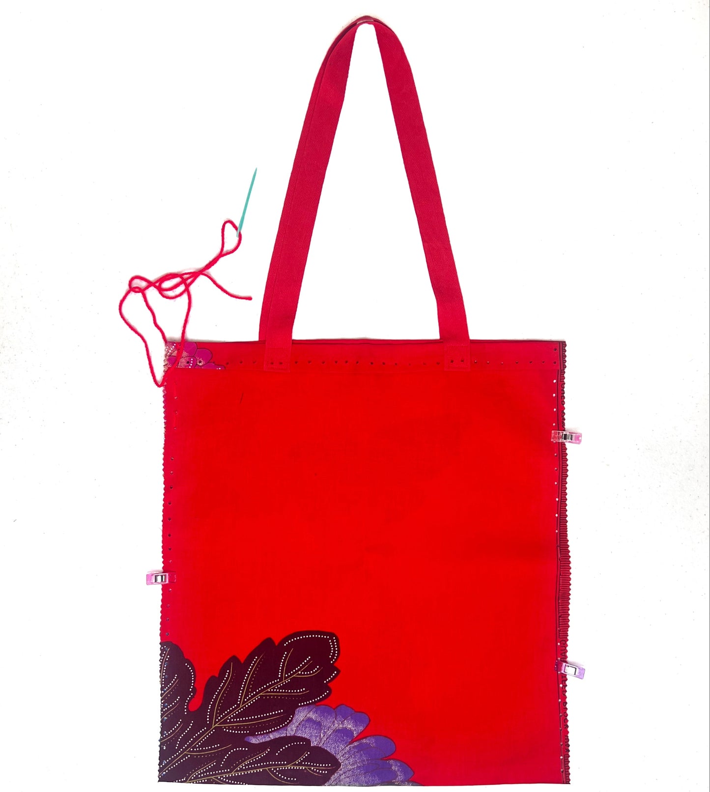 Red tote bag with floral design on a white background